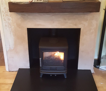 ACR Oakdale Multifuel Stove - in matt black with a slate hearth and rustic oak beam in Medium/ Dark finish. Installed in Pyrford near Woking, Surrey